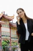 Businesswoman on mobile phone, Chinese temple in the background - Wang Leng