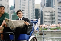 Businessman sitting in trishaw, holding newspaper - Alex Microstock02