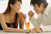 Couple sharing a drink, sitting face to face, holding hands - Alex Microstock02
