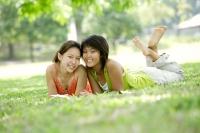 Two young women lying on grass, looking at camera - Alex Microstock02