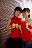 Young women dressed in red, holding two oranges and red packet, smiling at camera - Alex Microstock02