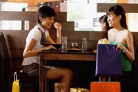 Young women in restaurant, looking at shopping bags - Alex Microstock02