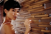 Young woman touching bamboo screen, looking at camera - Alex Microstock02