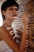 Young woman next to bamboo screen, looking at camera - Alex Microstock02