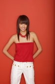 Young woman in red tube top standing against red wall - Yukmin