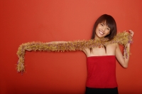 Young woman in red tube top holding feather boa - Yukmin