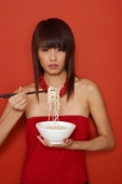 Young woman in red, holding bowl of noodles, looking at camera - Yukmin