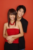 Couple standing against red wall, smiling at camera - Yukmin