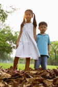 Children standing on pile of leaves, looking at camera - Yukmin