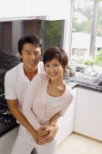 Couple embracing in kitchen, smiling at camera - Alex Mares-Manton