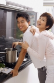 Man cooking on stove, woman embracing him from behind, both looking at camera - Alex Mares-Manton