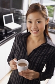 Female executive standing in kitchen, holding mug, smiling at camera - Alex Mares-Manton