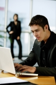 Male executive dressed in black, using laptop - Alex Mares-Manton