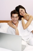 Couple on bed, looking at laptop - Yukmin