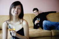 Couple sitting apart in living room, both looking at camera, focus on the man in the background - Yukmin