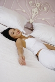 Woman lying on bed, looking at camera - Yukmin