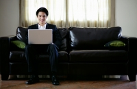 Man seating on sofa, using laptop - Yukmin