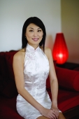 Woman dressed in Chinese cheongsam, sitting on sofa - Yukmin