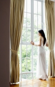 Woman looking out full length window - Yukmin