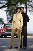 Well dressed couple standing side by side, looking at camera, car in the background - Alex Mares-Manton