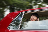 Woman sitting in car, using mobile phone, smiling - Alex Mares-Manton