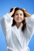 Young woman wearing white bathrobe, hands in hair, looking away - Alex Microstock02