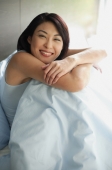Woman on bed hugging knees, arms crossed - Alex Mares-Manton
