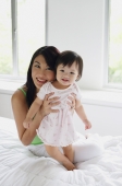 Mother embracing baby girl, smiling at camera - Alex Mares-Manton