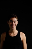 Man in black sleeveless top, standing against black background, looking at camera, smiling - Alex Microstock02