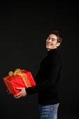 Man in black turtleneck carrying big red box with gold ribbon - Alex Microstock02