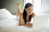 Woman in bedroom, using laptop - Alex Mares-Manton