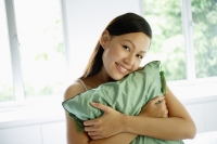 Woman hugging green cushion, smiling at camera - Alex Mares-Manton