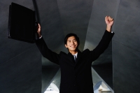 Businessman with arms raised, holding briefcase - Yukmin