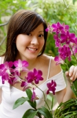 Young woman with orchid plant, smiling at camera - Alex Mares-Manton