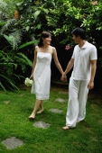 Couple walking in garden, holding hands - Alex Mares-Manton