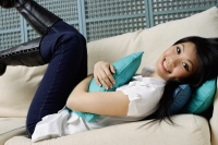 Young woman reclining on sofa, smiling at camera - Alex Mares-Manton