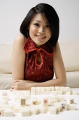 Young woman looking at camera, mahjong tiles in front of her - Alex Mares-Manton