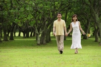 Mature couple walking in park, holding hands, smiling - Alex Mares-Manton
