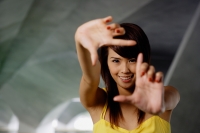 Woman making finger frame, smiling at camera - Yukmin