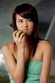 Woman in green top holding green apple, making a face - Yukmin