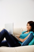 Woman on sofa, using laptop - Nugene Chiang
