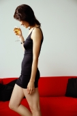 Woman in black dress, holding drink, looking down, side view - Nugene Chiang