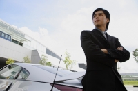 Businessman with arms crossed, leaning on car, looking away - Alex Mares-Manton