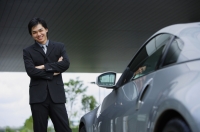 Businessman with arms crossed, standing next to car - Alex Mares-Manton