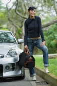 Woman holding bag, standing next to car, smiling at camera - Alex Mares-Manton