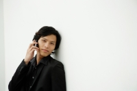 Businessman leaning on wall, using mobile phone - Yukmin