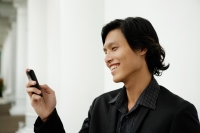 Businessman using mobile phone, text messaging - Yukmin