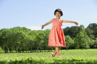 Girl walking on grass, arms outstretched, smiling - Alex Mares-Manton