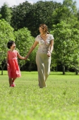 Mother and daughter, holding hands, walking on grass - Alex Mares-Manton