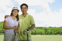 Couple standing side by side, holding golf clubs - Alex Mares-Manton